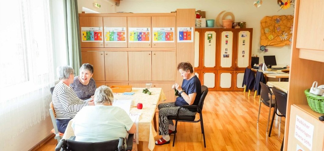 Gruppenraum: mehrere Personen sitzen gemeinsam an Tischen