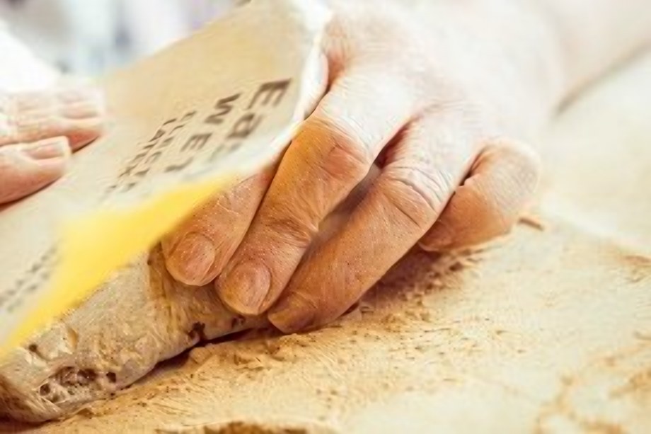 Hände schleifen ein Holzstück auf der Werkbank