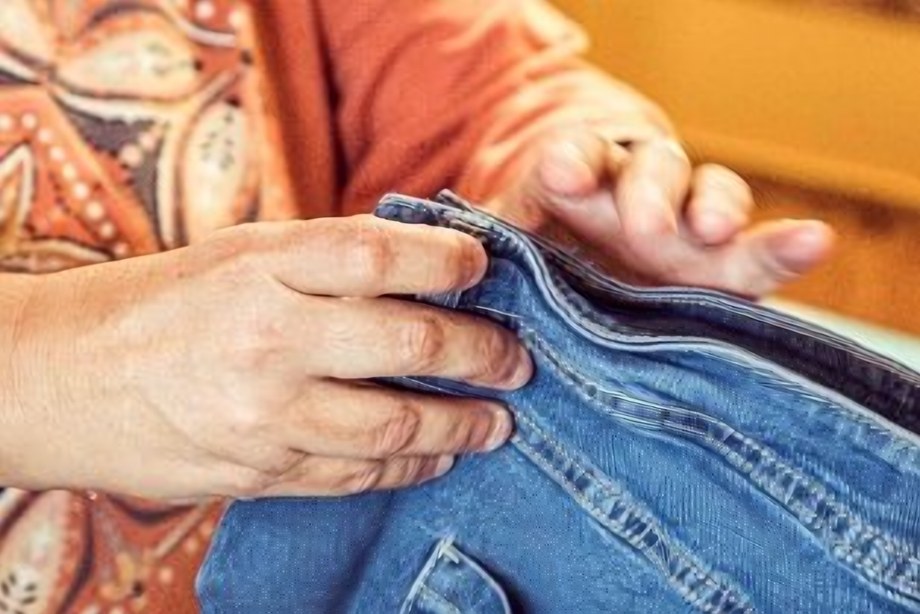 Hände nähen an einer Jeans
