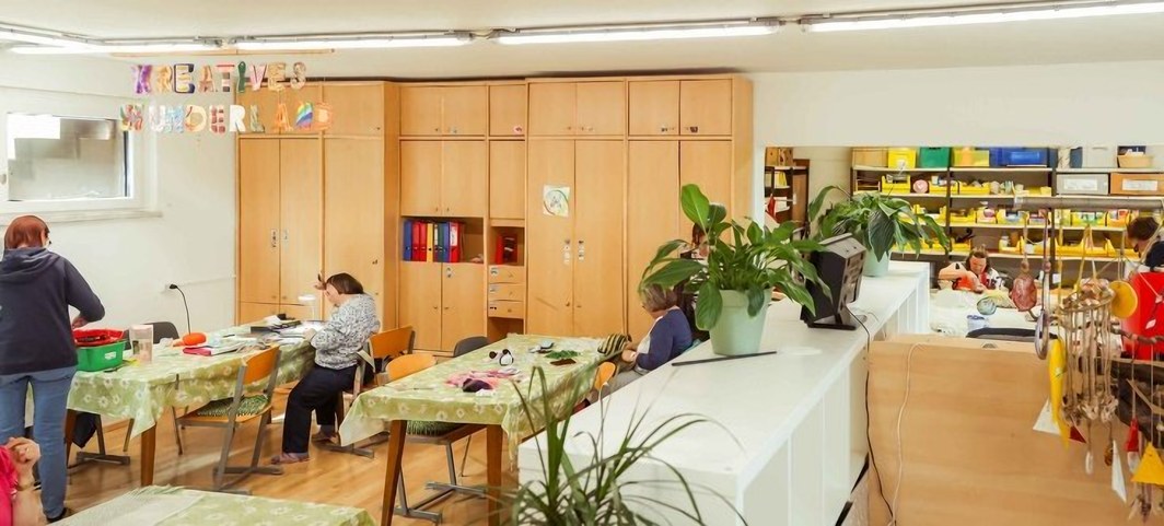 Kreativraum mit Arbeitstischen und gut gefüllten Materialregalen