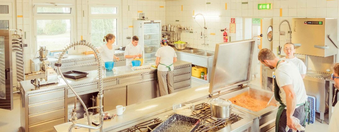 Blick in die Küche der Tageswerkstätte, mehrere Personen bei der Arbeit