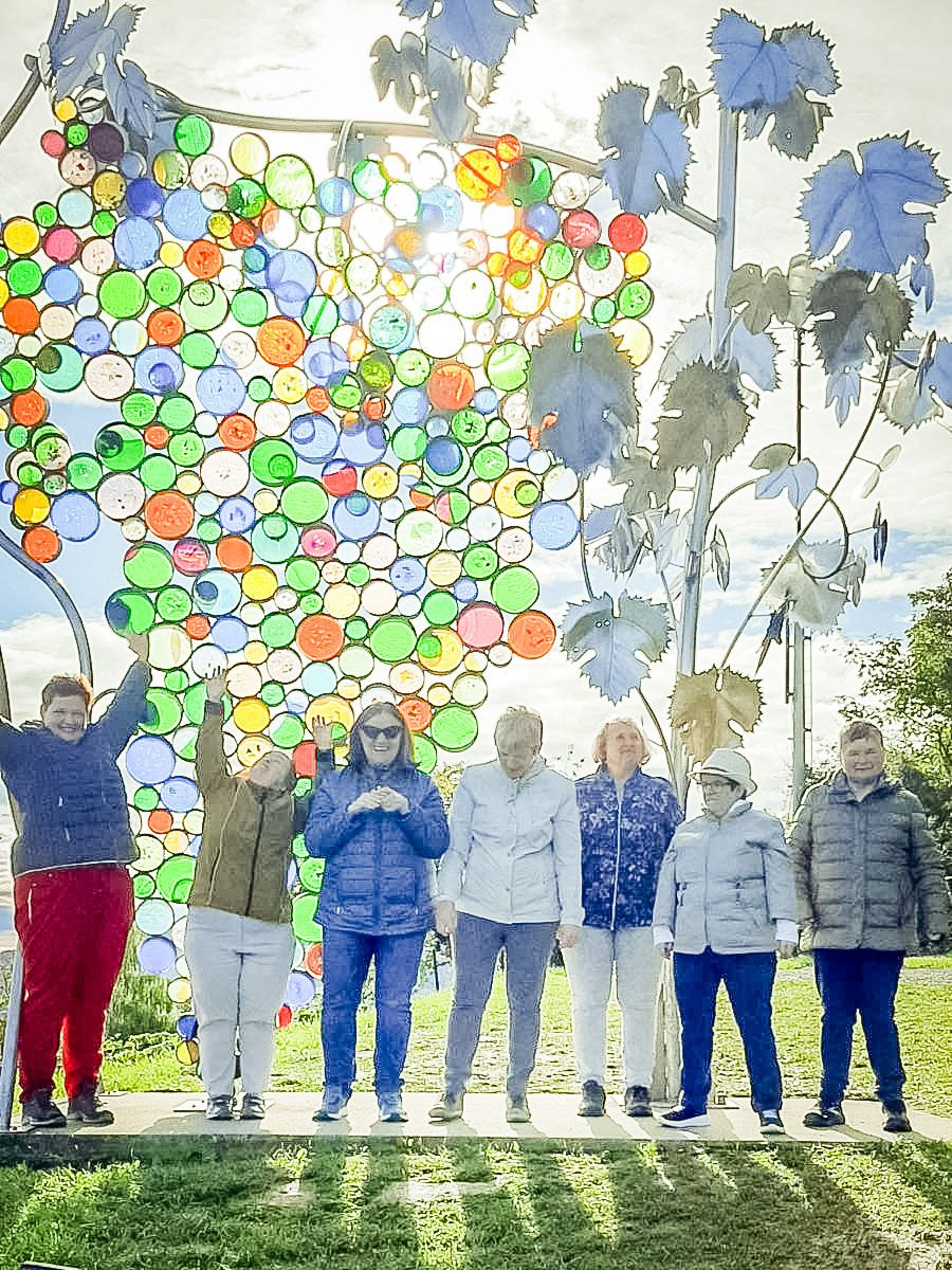 Eine Gruppe steht unter einem bunten Kunstobjekt aus farbigen Scheiben