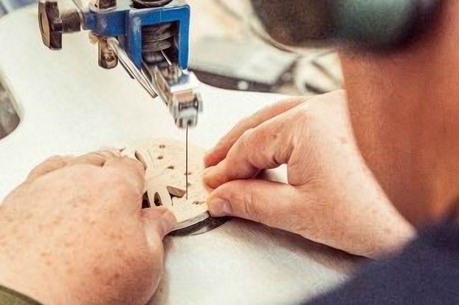 Hände führen ein Holzteil an einer Dekupiersäge