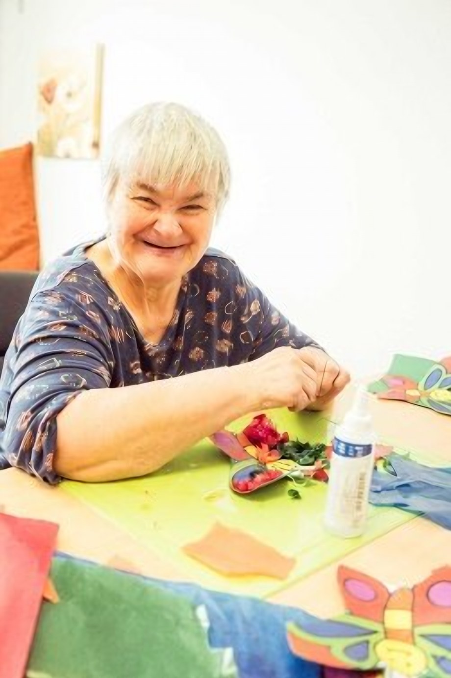 Eine Frau bastelt lachend bunte Schmetterlinge