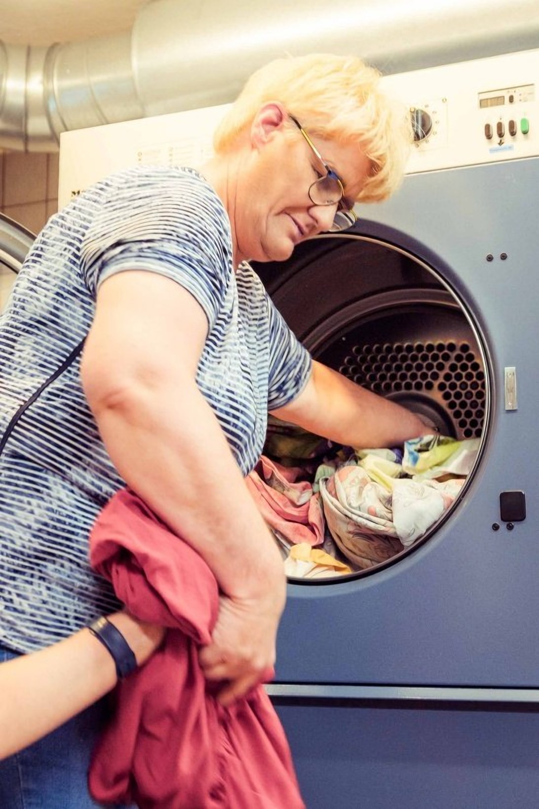 Eine Mitarbeiterin räumt Wäsche aus der Waschmaschine