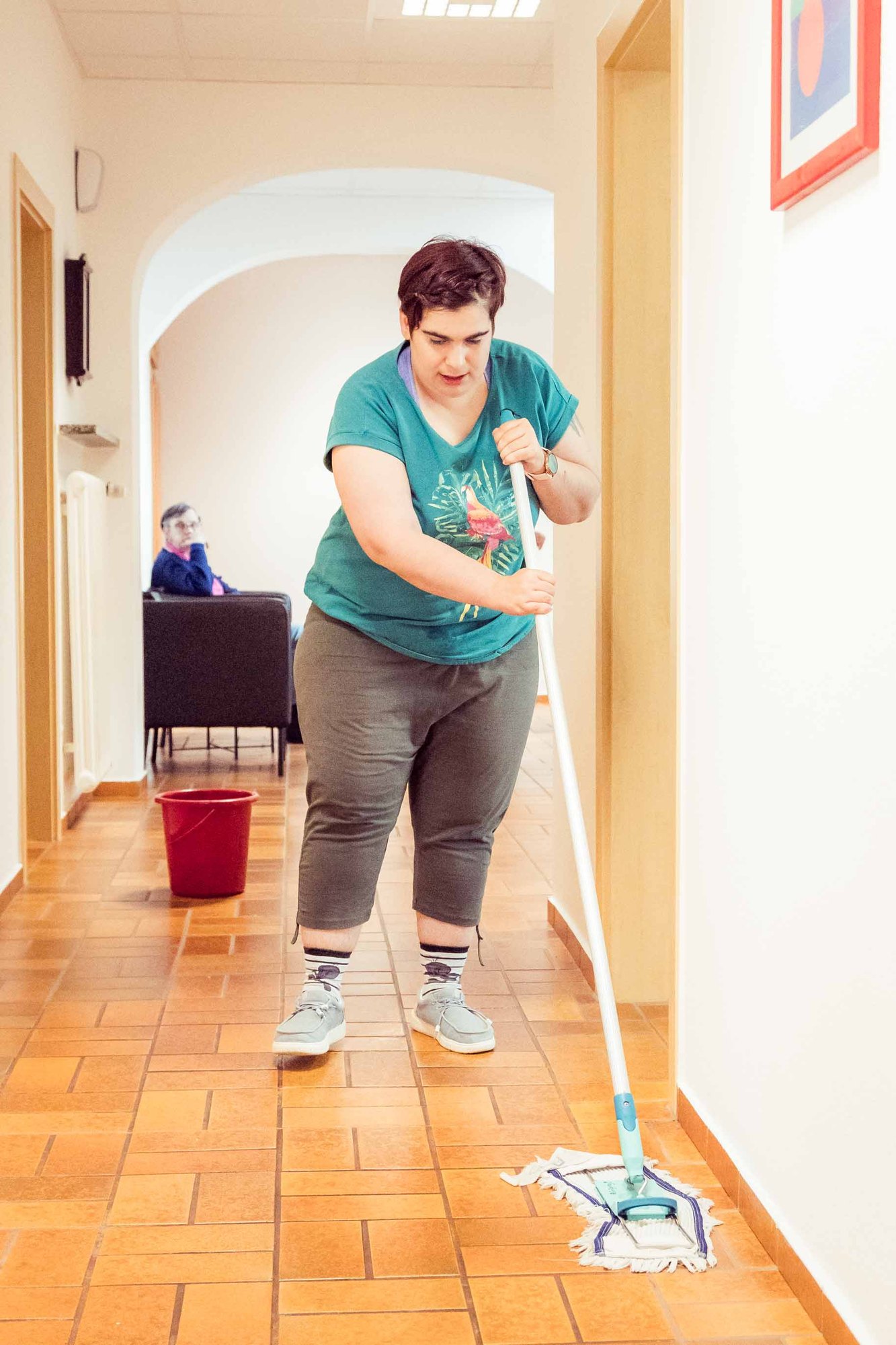 Eine Mitarbeiterin wischt den Boden im Gang