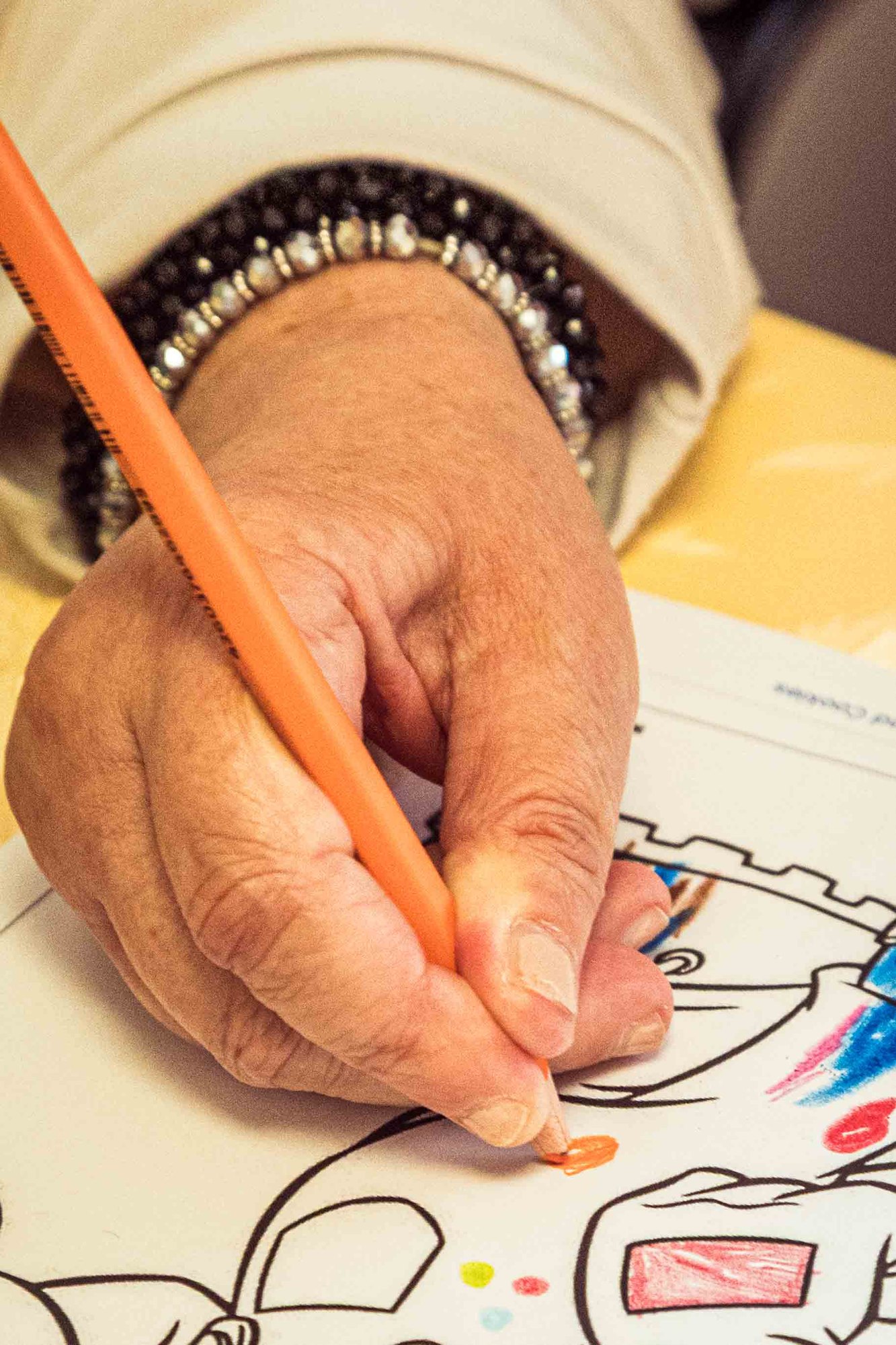 Eine Hand malt mit einem Buntstift ein Bild aus