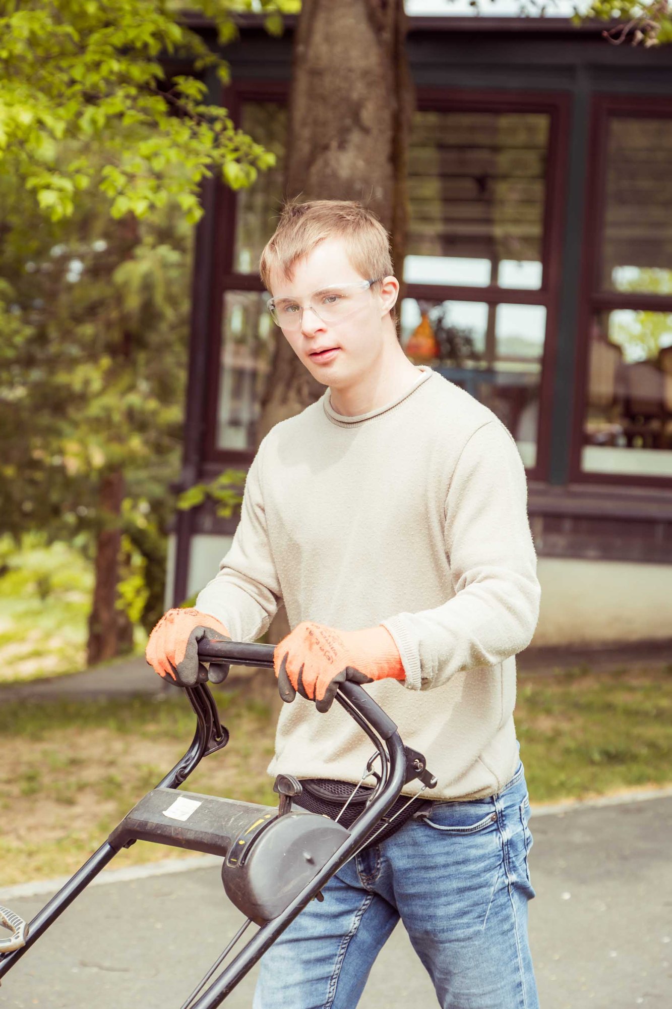 Ein junger Mitarbeiter mäht den Rasen vor dem Haus