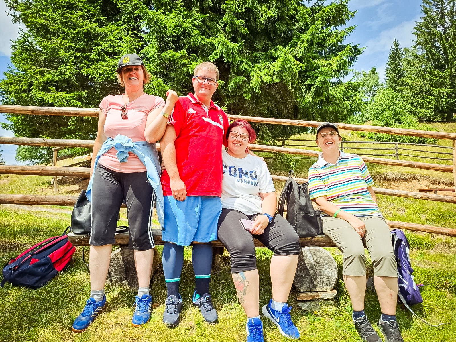 Vier Personen rasten bei einer Wanderung auf einer Bank